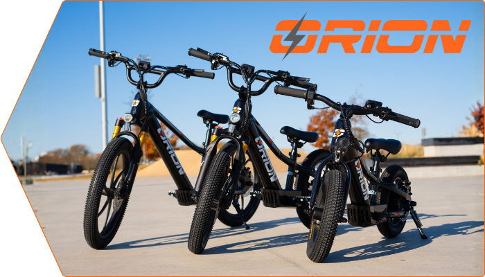 Three black Orion bikes on a sunny sidewalk.