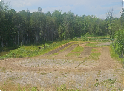 Dirt motorbike track in a forested area with trees in the background.